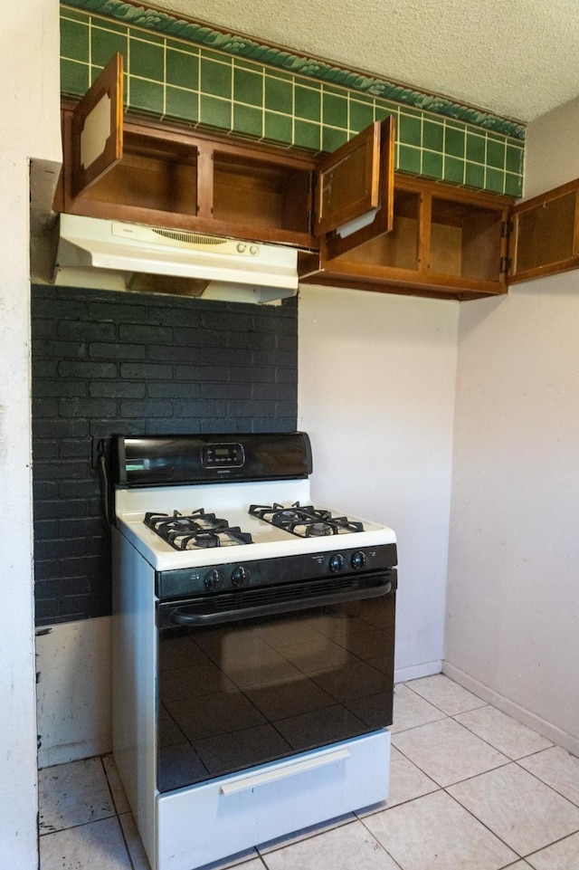 702 Meadowglen Dr, Baytown, TX 77521 - kitchen featuring gas stove, under cabinet range hood, a textured ceiling, and light tile patterned floors