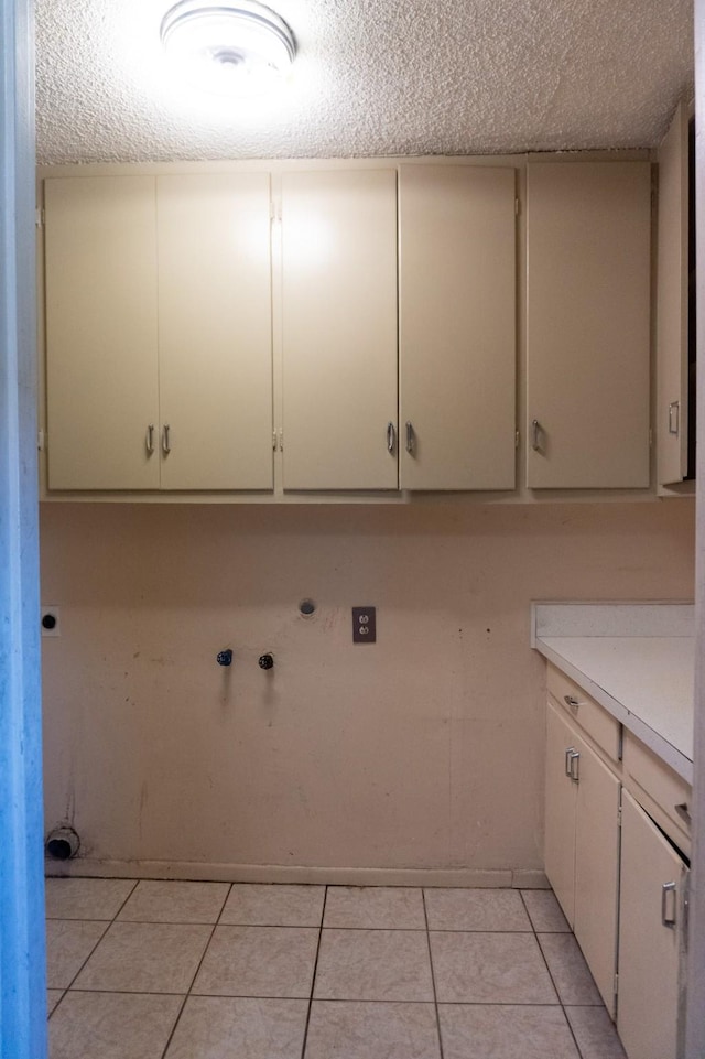702 Meadowglen Dr, Baytown, TX 77521 - washroom with cabinet space, light tile patterned flooring, a textured ceiling, hookup for a washing machine, and electric dryer hookup