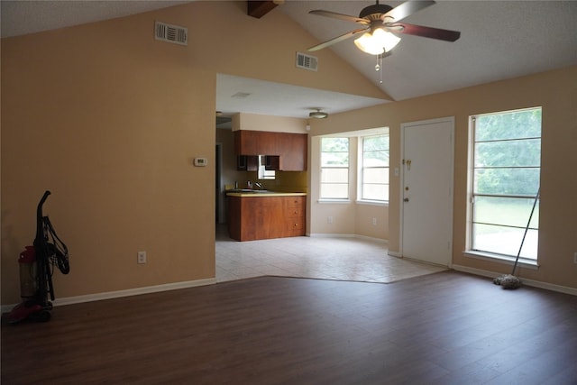 702 Meadowglen Dr, Baytown, TX 77521 - unfurnished living room featuring light wood-style floors, ceiling fan, beamed ceiling, and high vaulted ceiling