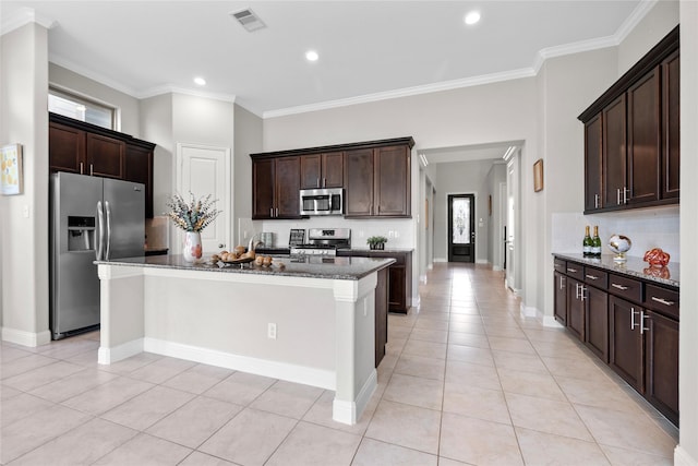 3507 Canyon Branch Ln, Fulshear, TX 77441 - kitchen featuring stainless steel appliances, dark stone countertops, light tile patterned floors, dark brown cabinetry, and ornamental molding