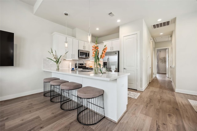 9504 Retriever Way, Houston, TX 77055 - kitchen featuring appliances with stainless steel finishes, a peninsula, light wood-type flooring, a breakfast bar area, and recessed lighting
