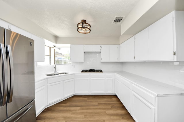 4203 Steep Rock Dr, Pasadena, TX 77504 - kitchen featuring stainless steel appliances, a sink, a textured ceiling, white cabinets, and decorative backsplash