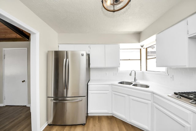 4203 Steep Rock Dr, Pasadena, TX 77504 - kitchen featuring appliances with stainless steel finishes, a sink, light wood-style floors, light countertops, and white cabinets