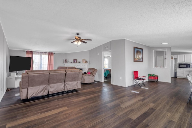 497 Rd 5603, Cleveland, TX 77327 - living area featuring a textured ceiling, dark wood-style flooring, ceiling fan, a fireplace, and baseboards