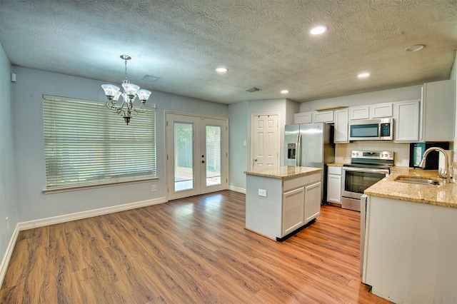7022 Raven Cliffs Ln, Spring, TX 77379 - kitchen featuring stainless steel appliances, wood finished floors, a center island, a textured ceiling, and french doors