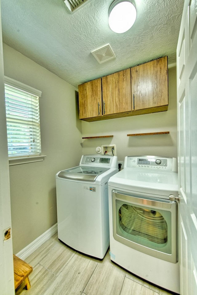 7022 Raven Cliffs Ln, Spring, TX 77379 - laundry room featuring cabinet space, separate washer and dryer, light wood-type flooring, and a textured ceiling