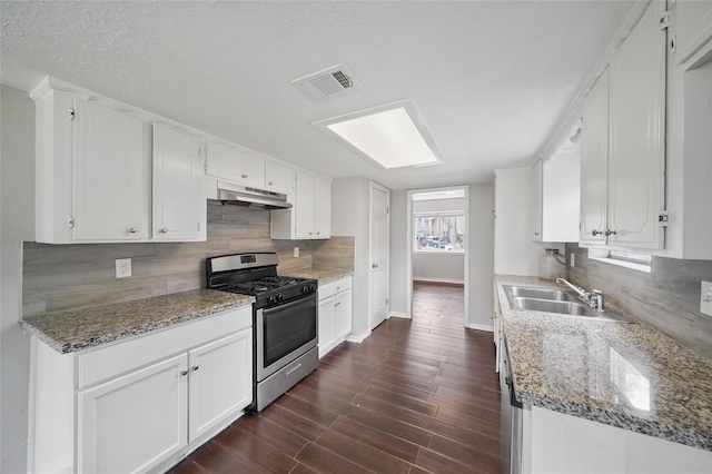 2251 Middle Creek Dr, Houston, TX 77339 - kitchen with gas stove, under cabinet range hood, baseboards, and decorative backsplash