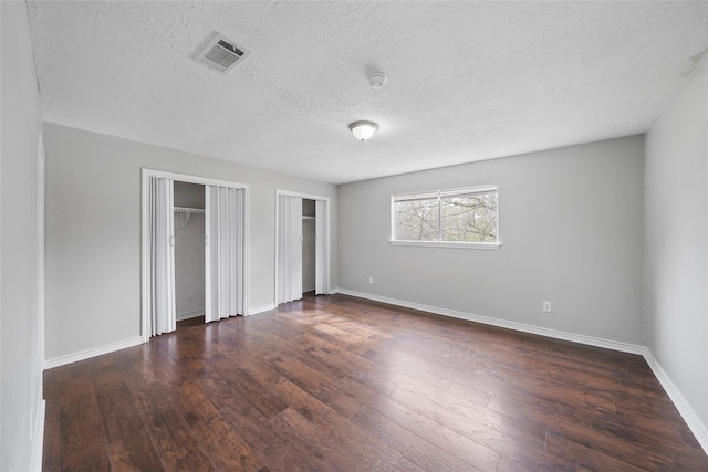 2251 Middle Creek Dr, Houston, TX 77339 - unfurnished bedroom with two closets, a textured ceiling, wood-type flooring, and baseboards