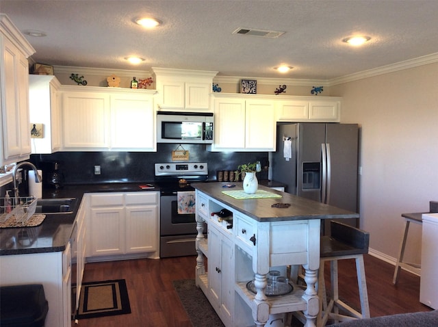 915 Sandollar, Crystal Beach, TX 77650 - kitchen featuring stainless steel appliances, dark countertops, a sink, crown molding, and dark wood-type flooring
