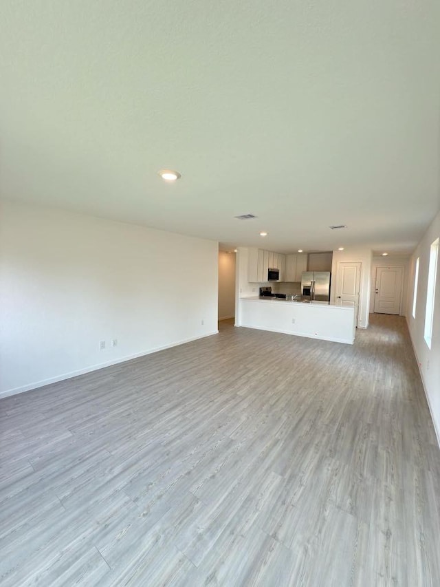 21026 Newberry Grove Ln, Humble, TX 77338 - unfurnished living room with light wood-style flooring, recessed lighting, and baseboards