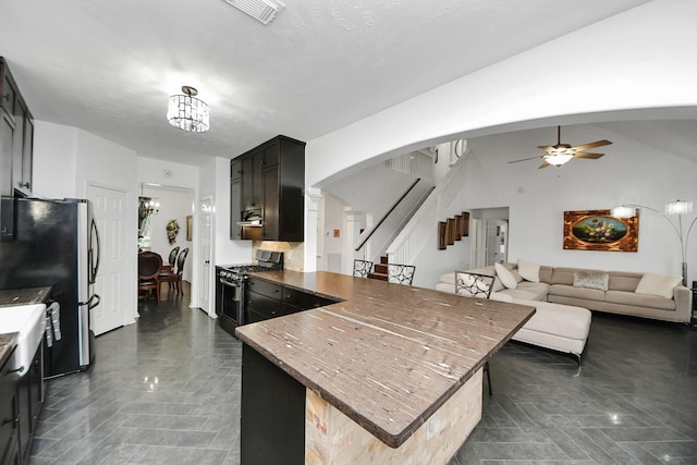 7410 Lassiter Hollow Ln, Richmond, TX 77407 - kitchen featuring stainless steel appliances, arched walkways, a peninsula, ceiling fan, and dark stone counters