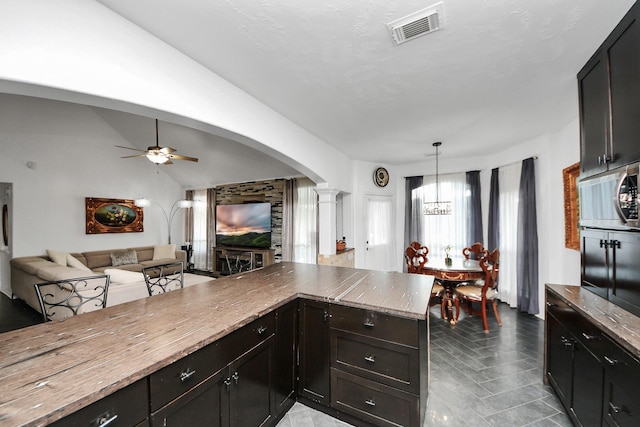 7410 Lassiter Hollow Ln, Richmond, TX 77407 - kitchen with arched walkways, decorative columns, open floor plan, ceiling fan, and stainless steel microwave