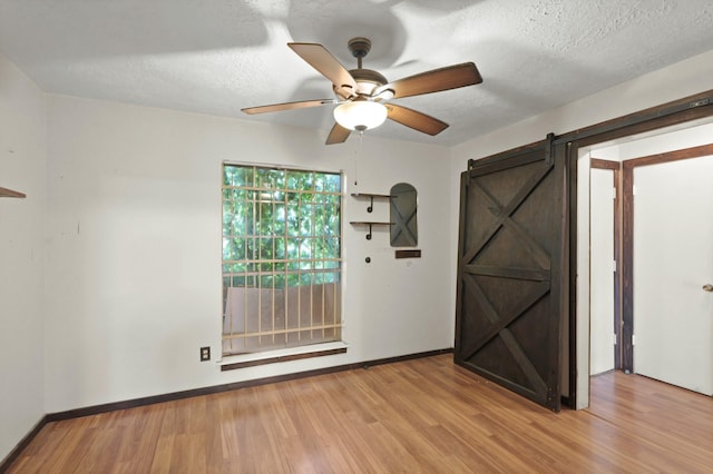 1318 Epsilon St, Pasadena, TX 77504 - unfurnished room with ceiling fan, a barn door, wood finished floors, baseboards, and a textured ceiling