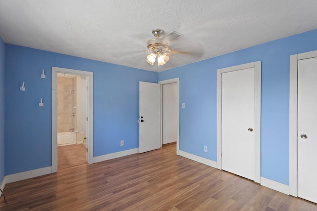 1318 Epsilon St, Pasadena, TX 77504 - unfurnished bedroom featuring baseboards, wood finished floors, a textured ceiling, and ensuite bathroom