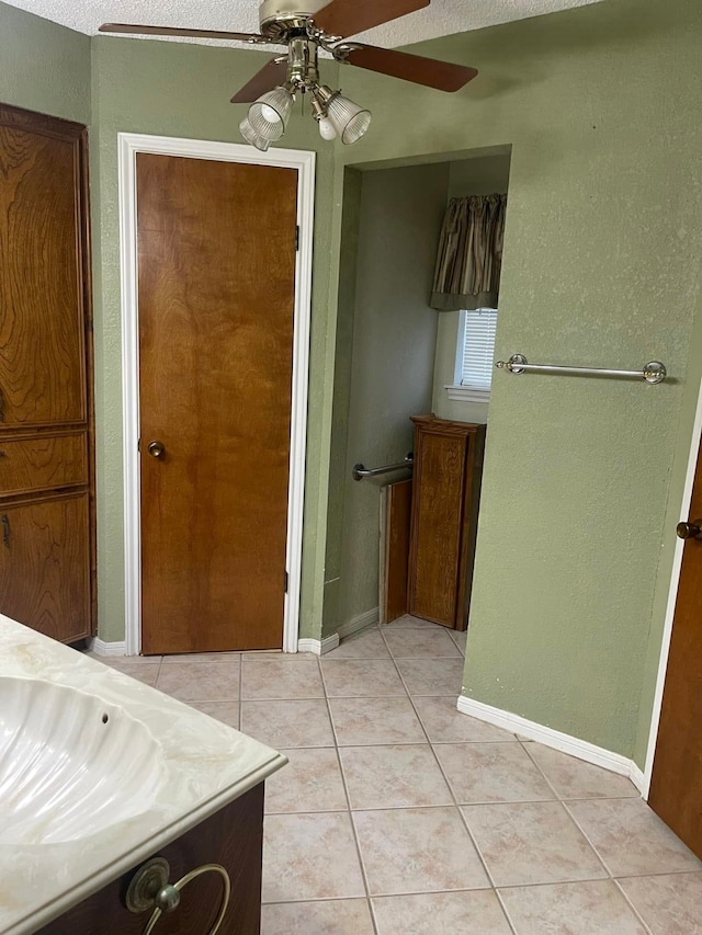 2724 22nd Ave N, Texas City, TX 77590 - bathroom featuring tile patterned floors, a ceiling fan, baseboards, a textured wall, and a sink