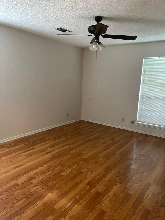 2724 22nd Ave N, Texas City, TX 77590 - empty room with wood finished floors, a ceiling fan, a textured ceiling, and baseboards