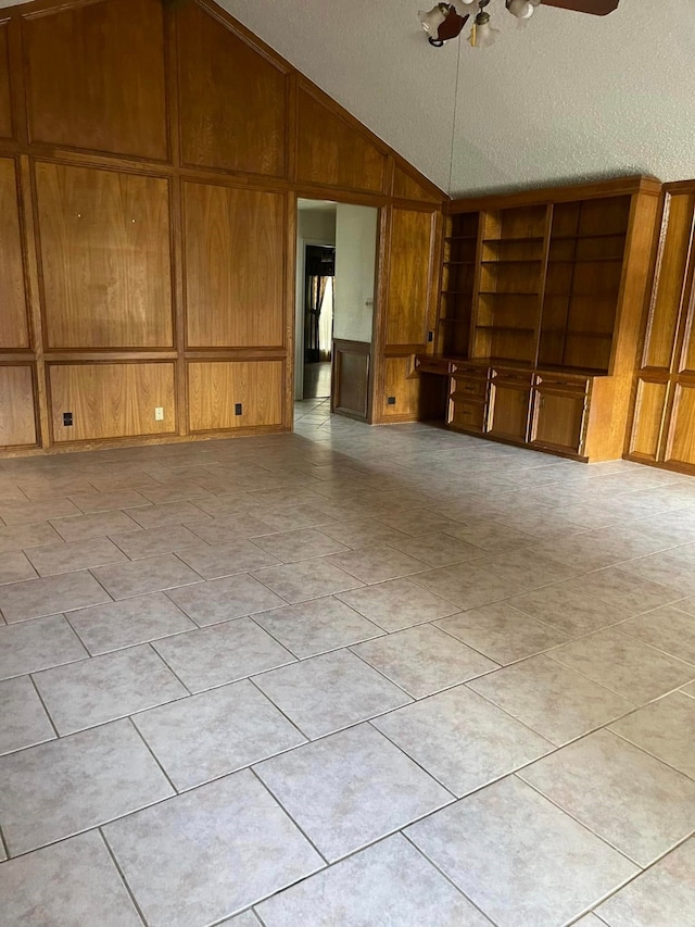 2724 22nd Ave N, Texas City, TX 77590 - unfurnished living room featuring vaulted ceiling, wood walls, a textured ceiling, a ceiling fan, and light tile patterned flooring