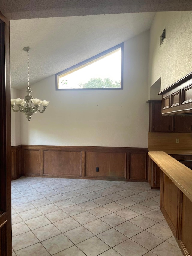 2724 22nd Ave N, Texas City, TX 77590 - spare room featuring a chandelier, lofted ceiling, wainscoting, light tile patterned flooring, and a textured ceiling