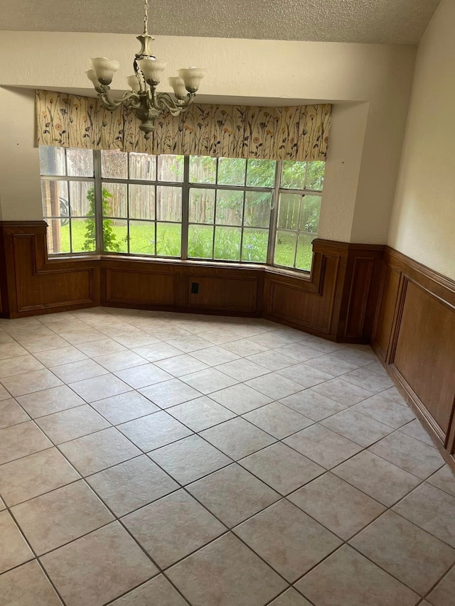 2724 22nd Ave N, Texas City, TX 77590 - unfurnished dining area featuring a chandelier, a textured ceiling, a wainscoted wall, plenty of natural light, and light tile patterned floors