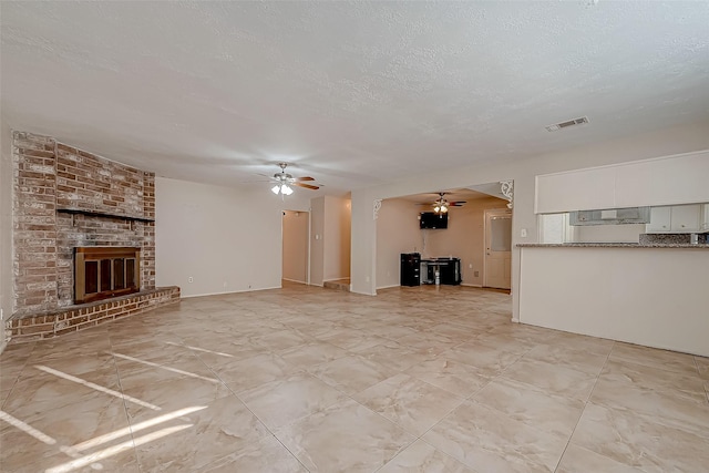 7650 Smiling Wood Ln, Houston, TX 77086 - unfurnished living room featuring a ceiling fan, a brick fireplace, and a textured ceiling