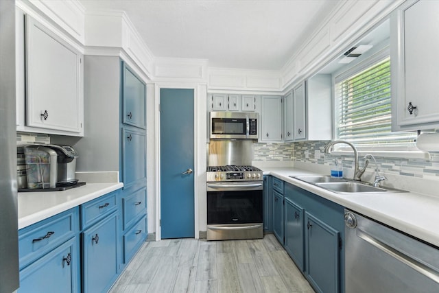 1926 Meadow Creek Dr, Pearland, TX 77581 - kitchen with appliances with stainless steel finishes, blue cabinets, a sink, tasteful backsplash, and light countertops