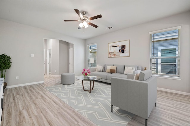 24708 Sonora Crescent Cir, Huffman, TX 77336 - living room featuring arched walkways, ceiling fan, light wood-type flooring, and baseboards