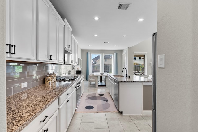 20714 Fertile Valley Ln, Richmond, TX 77407 - kitchen with appliances with stainless steel finishes, decorative backsplash, dark stone countertops, light tile patterned floors, and a sink
