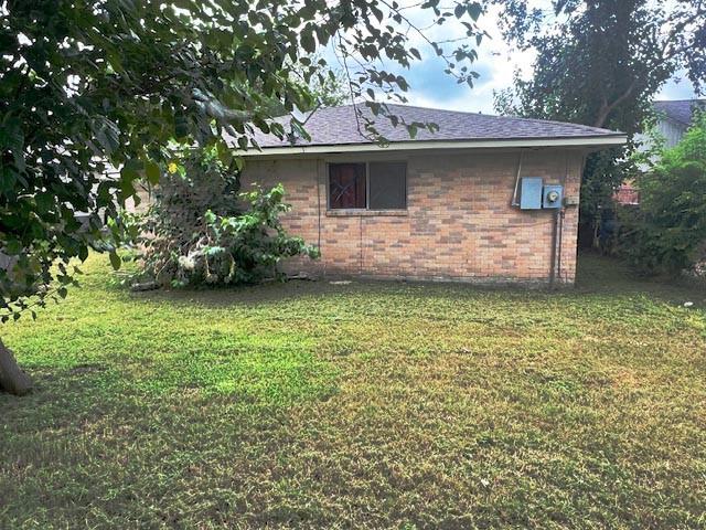 12922 Claygate Dr, Houston, TX 77047 - view of property exterior featuring a yard, brick siding, and a shingled roof
