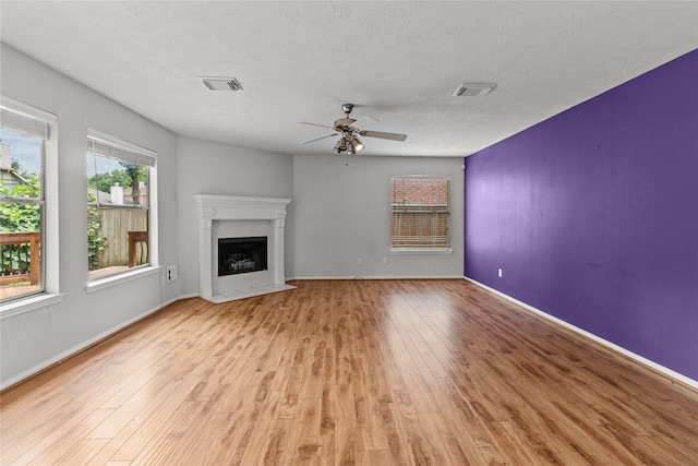 16418 Great Frst, Humble, TX 77346 - unfurnished living room featuring a ceiling fan, a fireplace with flush hearth, light wood-style flooring, and a textured ceiling