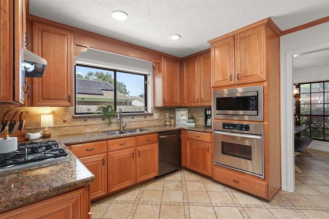 939 Mulberry Ridge Way, Houston, TX 77062 - kitchen featuring appliances with stainless steel finishes, a sink, tasteful backsplash, brown cabinetry, and light tile patterned floors