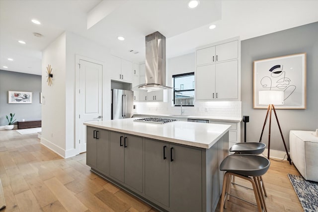 823 Aurora St, Houston, TX 77009 - kitchen with appliances with stainless steel finishes, exhaust hood, white cabinetry, light wood-type flooring, and backsplash