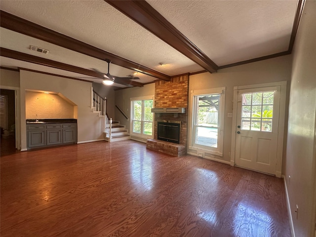 5306 Manor Glen Dr, Kingwood, TX 77345 - unfurnished living room featuring a textured ceiling, stairway, wood finished floors, beam ceiling, and a fireplace