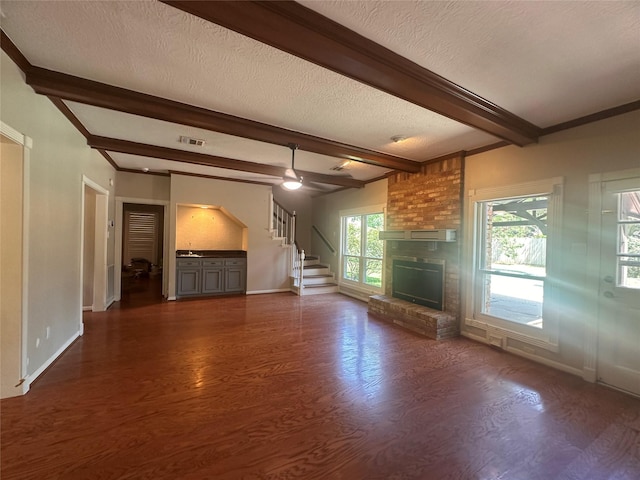 5306 Manor Glen Dr, Kingwood, TX 77345 - unfurnished living room featuring beam ceiling, dark wood-style flooring, a textured ceiling, a fireplace, and baseboards