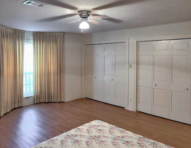 409 W Collier St, Jasper, TX 75951 - unfurnished bedroom with two closets, wood finished floors, a ceiling fan, and baseboards