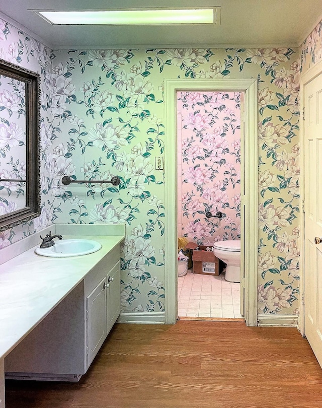409 W Collier St, Jasper, TX 75951 - bathroom featuring wallpapered walls, toilet, wood finished floors, vanity, and baseboards