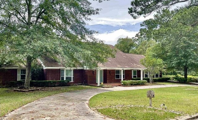 409 W Collier St, Jasper, TX 75951 - ranch-style home with a front lawn, curved driveway, and brick siding