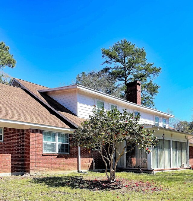 409 W Collier St, Jasper, TX 75951 - rear view of house featuring a chimney, brick siding, roof with shingles, and a lawn