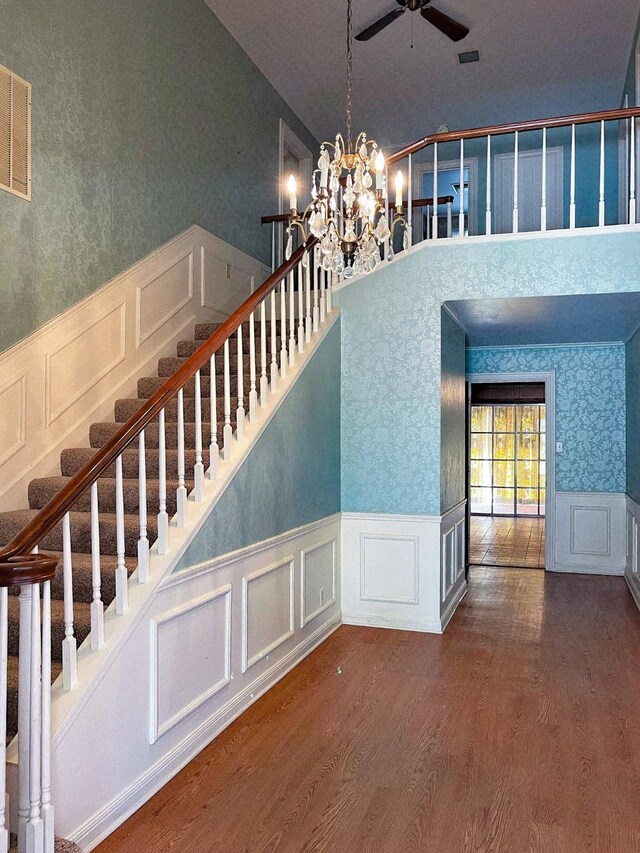 409 W Collier St, Jasper, TX 75951 - stairs featuring a decorative wall, ceiling fan, wood finished floors, wainscoting, and a towering ceiling