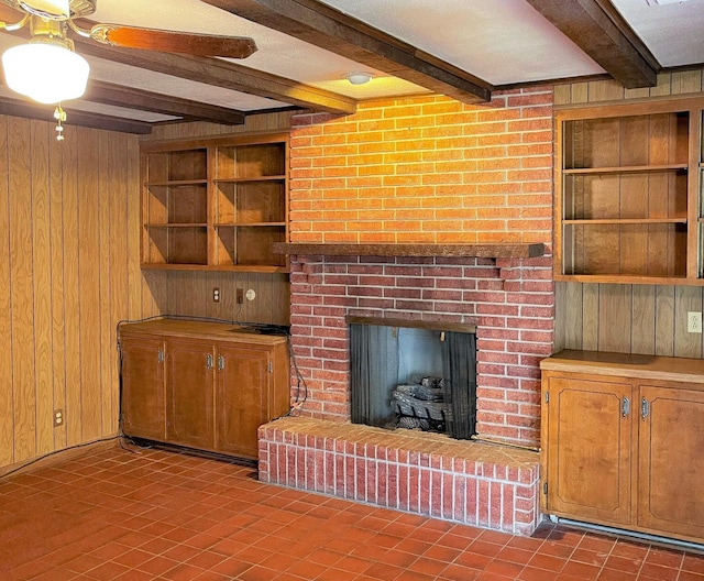 409 W Collier St, Jasper, TX 75951 - unfurnished living room with wooden walls, beam ceiling, a brick fireplace, built in shelves, and tile patterned flooring