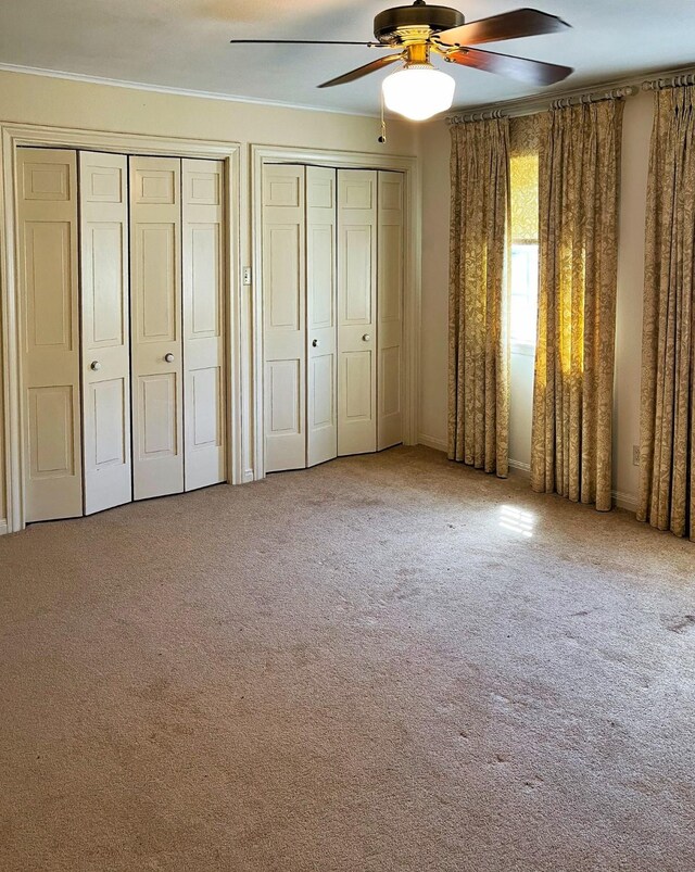 409 W Collier St, Jasper, TX 75951 - unfurnished bedroom with two closets, carpet floors, ornamental molding, and a ceiling fan