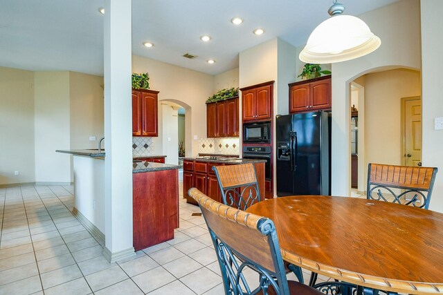 14719 Golden Bough Ln, Humble, TX 77396 - kitchen with black appliances, arched walkways, reddish brown cabinets, light tile patterned floors, and decorative backsplash