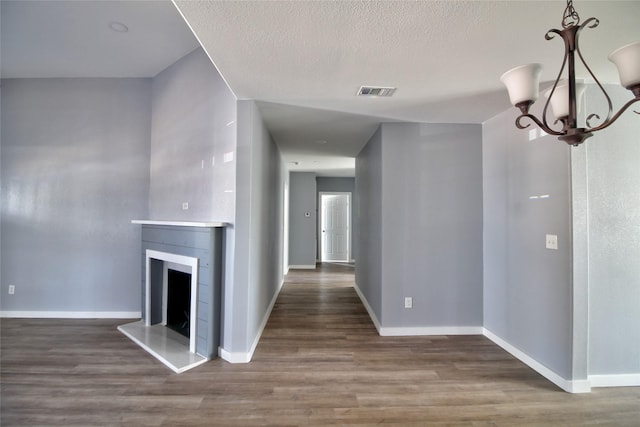 322 Montrose St, Lufkin, TX 75901 - unfurnished living room featuring a chandelier, wood finished floors, baseboards, a fireplace with raised hearth, and a textured ceiling