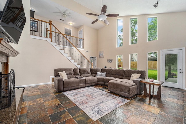 11607 Leaning Pine Dr, Houston, TX 77070 - living room featuring stone tile floors, a ceiling fan, a towering ceiling, stairway, and baseboards