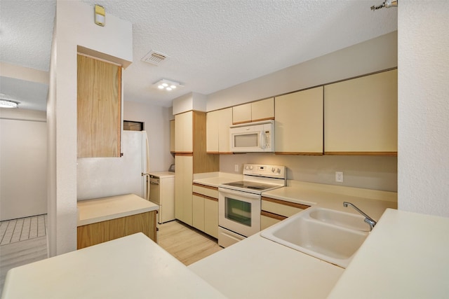 7700 Seawall Blvd Unit 512, Galveston, TX 77551 - kitchen featuring white appliances, a textured ceiling, light wood finished floors, light countertops, and cream cabinets