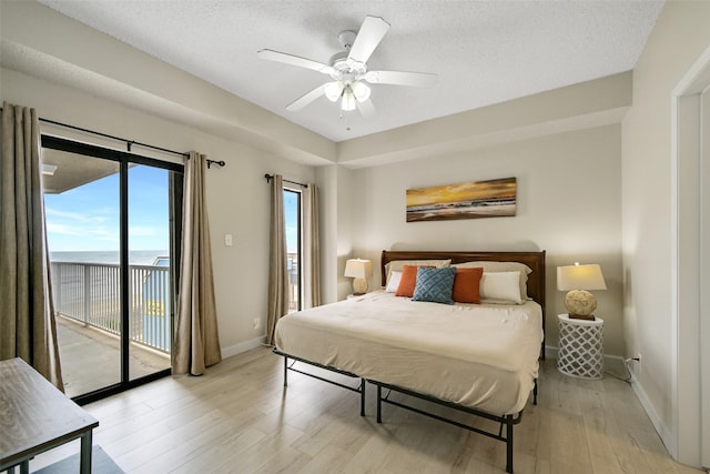 7700 Seawall Blvd Unit 512, Galveston, TX 77551 - bedroom with access to outside, light wood-style floors, a water view, a textured ceiling, and a ceiling fan