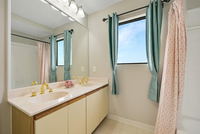 7700 Seawall Blvd Unit 512, Galveston, TX 77551 - full bath featuring healthy amount of natural light, double vanity, a textured ceiling, and tile patterned floors