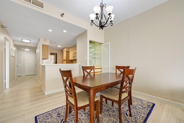 7700 Seawall Blvd Unit 512, Galveston, TX 77551 - dining area with a chandelier, light wood-style floors, a textured ceiling, and recessed lighting