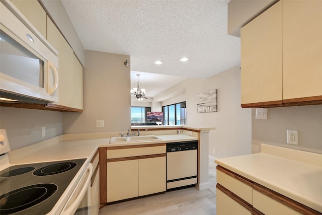 7700 Seawall Blvd Unit 512, Galveston, TX 77551 - kitchen with white appliances, a peninsula, a textured ceiling, cream cabinetry, and a chandelier