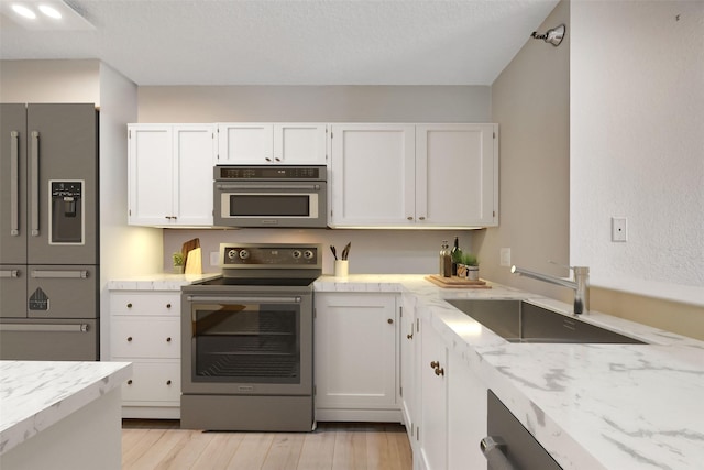 7700 Seawall Blvd Unit 512, Galveston, TX 77551 - kitchen with stainless steel appliances, white cabinets, light wood finished floors, and light stone counters