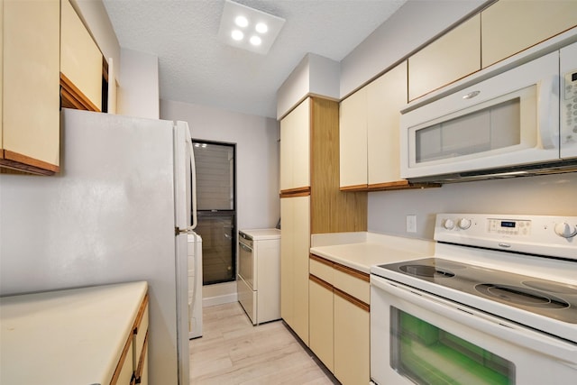 7700 Seawall Blvd Unit 512, Galveston, TX 77551 - kitchen featuring white appliances, washer / dryer, light wood finished floors, light countertops, and cream cabinets